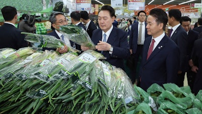 South Korean President Yoon Suk Yeol, center, checks the price of green onions at Nonghyup Hanaro Mart, Seoul, March 18, 2024.