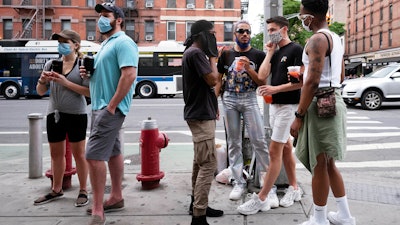 People wait for takeout drinks at a bar in the Hell's Kitchen neighborhood of New York, May 29, 2020.