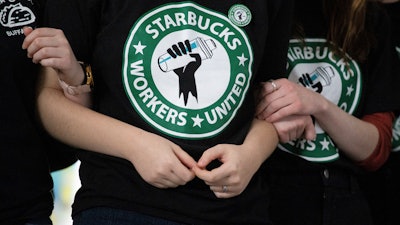 Starbucks employees and supporters link arms during a union election watch party, Buffalo, N.Y., Dec. 9, 2021.