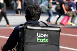 An Uber Eats delivery person rides a bicycle through the Shinjuku district in Tokyo, April 28, 2021.