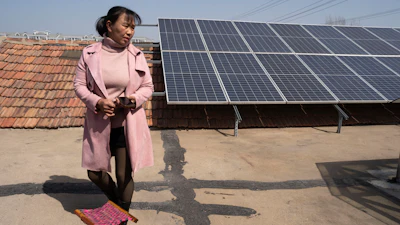 Shi Mei walks near solar panels on her rooftop outside Jinan, China, March 21, 2024.