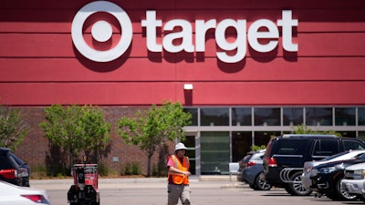 A worker collects shopping carts in the parking lot of a Target in Highlands Ranch, Colo., June 9, 2021.