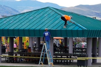 Workers paint the roof a picnic area in Clement Park, Littleton, Colo., April 17, 2024.