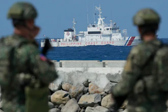 Philippine troops watch a Philippine coast guard ship.
