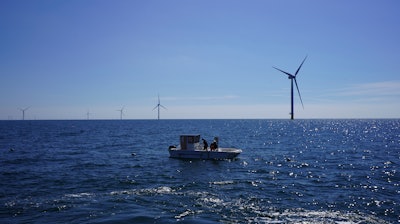 Workers aboard a small boat check lines of seaweed and mussels crops at Kriegers Flak offshore wind farm.