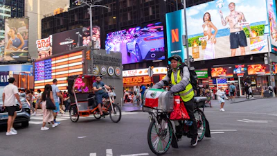 Sergio Solano, an immigrant from Mexico, rides his bicycle through Times Square while making a delivery.