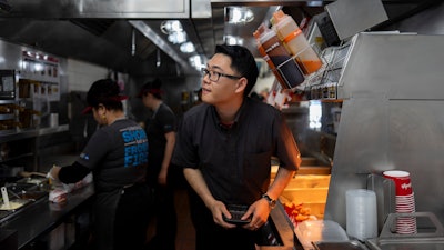 Lawrence Cheng, whose family owns seven Wendy's locations south of Los Angeles, works in the kitchen at his Wendy's restaurant in Fountain Valley, Calif.