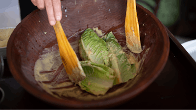 Salad Master Efrain Montoya mixes Romaine leaves with other ingredients as he prepares a Caesar salad at Ceasar's restaurant Thursday, June 27, 2024, in Tijuana, Mexico.