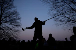 Mark Duffy, a member of the Red Cliff Band of Lake Superior Chippewa, stands on a picnic table while showing kids how to spearfish at a family and youth spearfishing event on Namekagon Lake.