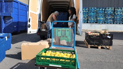 Manuel Pintos, a volunteer for Le Maillon, loads goods into a vehicle.