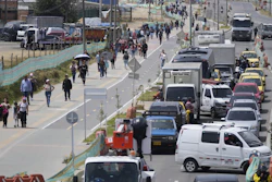 Commuters walk along an avenue blocked by truckers protesting a government-announced increase in diesel prices in Bogota, Colombia.