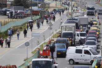 Commuters walk along an avenue blocked by truckers protesting a government-announced increase in diesel prices in Bogota, Colombia.