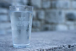 Glass of water with a Virginia Tech logo.