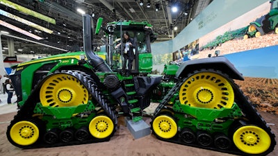A convention goer exits a John Deere 9RX Tractor at the John Deere booth during the CES tech show, Las Vegas, Jan. 7, 2025.