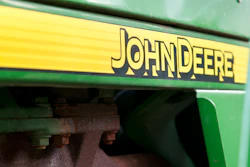 The John Deere logo on the side of a tractor.