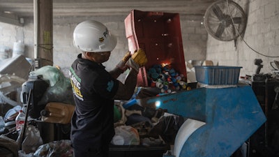 Jesus Cuevas, a Petgas technician, puts plastic caps into a shredding machine inside a recycling center in Boca del Rio, Veracruz, Mexico, Jan. 4, 2025.