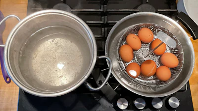 A photo provided by researchers in February 2025 shows two pots, one with boiling water, left, and the other with a basket of eggs in lukewarm water, in a new method of boiling eggs dubbed 'periodic cooking.'