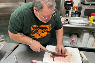 Sam Bohr cuts raw coyote meat before it was cooked and served at a wild game dinner in Pine Grove, Pa., Feb. 15, 2025.
