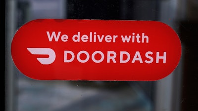 A DoorDash sign posted on the door of a Dunkin' Donuts franchise, Feb. 27, 2023, Methuen, Mass.