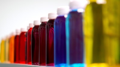 Bottles containing a variety of colored liquids sit on a shelf in a lab at Sensient Technologies Corp., St. Louis, April 2, 2025.