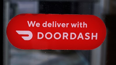 A DoorDash sign is posted on the door of a Dunkin' Donuts franchise, Feb. 27, 2023, Methuen, Mass.