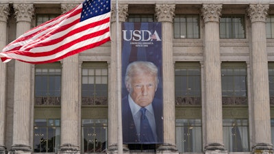 A banner with a photograph of President Donald Trump hangs near the entrance of the U.S. Department of Agriculture building in Washington, Friday, May 16, 2025.