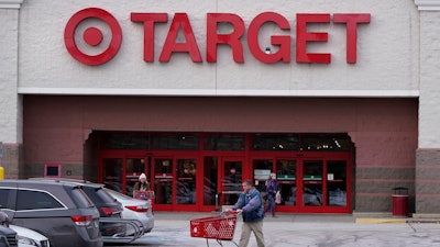A shopper wheels a cart through the parking lot after making a purchase at the Target store, Monday, Feb. 27, 2023, in Salem, N.H.