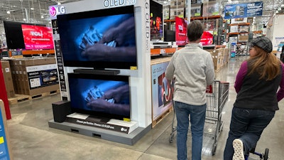 Shoppers pass by televisions on display in a Costco warehouse, Colorado Springs, Colo, Dec. 19, 2024.