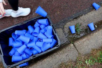 A runner discards a reusable silicone cup by Hiccup during the PNC Women Run the Cities race, May 17, 2025, Minneapolis.