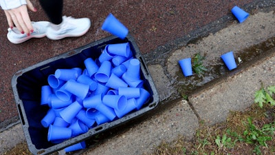 A runner discards a reusable silicone cup by Hiccup during the PNC Women Run the Cities race, May 17, 2025, Minneapolis.