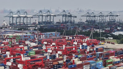 Trucks loaded with container move through a container terminal port in Shanghai, China Monday, June 9, 2025.