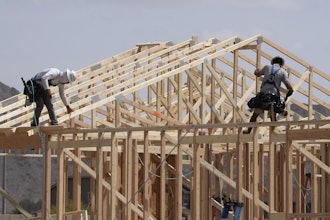 Construction workers frame up a roof of wood lumber at a new home build, April 1, 2025, in Laveen, Ariz.