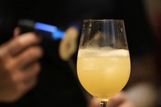 A bartender applies heat to a slice of dried pear as he prepares a cocktail named 'Beijing Beijing' at a bar in Beijing, June 13, 2025.