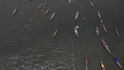 Artisanal fishing boats sit in the water outside the fish landing site in Tanji, Gambia, on March 25, 2025.
