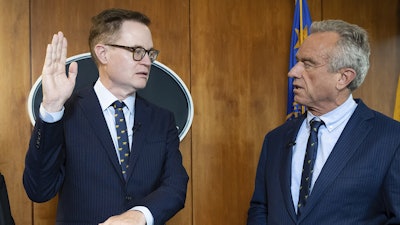 In this photo provided by the Department of Health and Human Secretary, Robert F. Kennedy, Jr., right, conducts the swearing-in ceremony of Jim O'Neill as the Department's Deputy Secretary, June 9, 2025, in Washington.