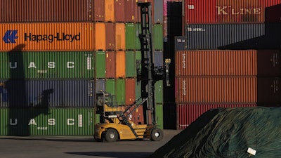 A heavy machine drives past shipping containers stacked at a depo, in Johannesburg, South Africa, Friday, Aug. 1, 2025.