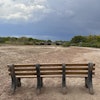 A park bench sits in the dry riverbed of the Rio Grande as traffic crosses a bridge along historic Route 66 in Albuquerque, N.M., on Thursday, Aug. 21, 2025.
