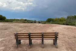A park bench sits in the dry riverbed of the Rio Grande as traffic crosses a bridge along historic Route 66 in Albuquerque, N.M., on Thursday, Aug. 21, 2025.