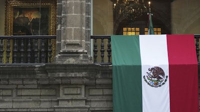 A Mexican flag hangs at the National Palace, where a portrait of former Mexico President Andres Manuel Lopez Obrador hangs, as President Claudia Sheinbaum delivers her first state-of-the-nation address in Mexico City, Monday, Sept. 1, 2025.