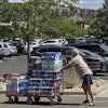 A shopper pushes a cart loaded with paper goods through the parking lot of a Costco warehouse, Aug. 12, 2025, Colorado Springs, Colo.