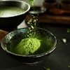 Matcha powder being added to a bowl.
