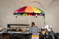 Street vendor Francisca, an immigrant from Guatemala, prepares an order at her cart in Los Angeles, Tuesday, Aug. 5, 2025, where her son accompanies her to help monitor their surroundings amid ongoing ICE raids.