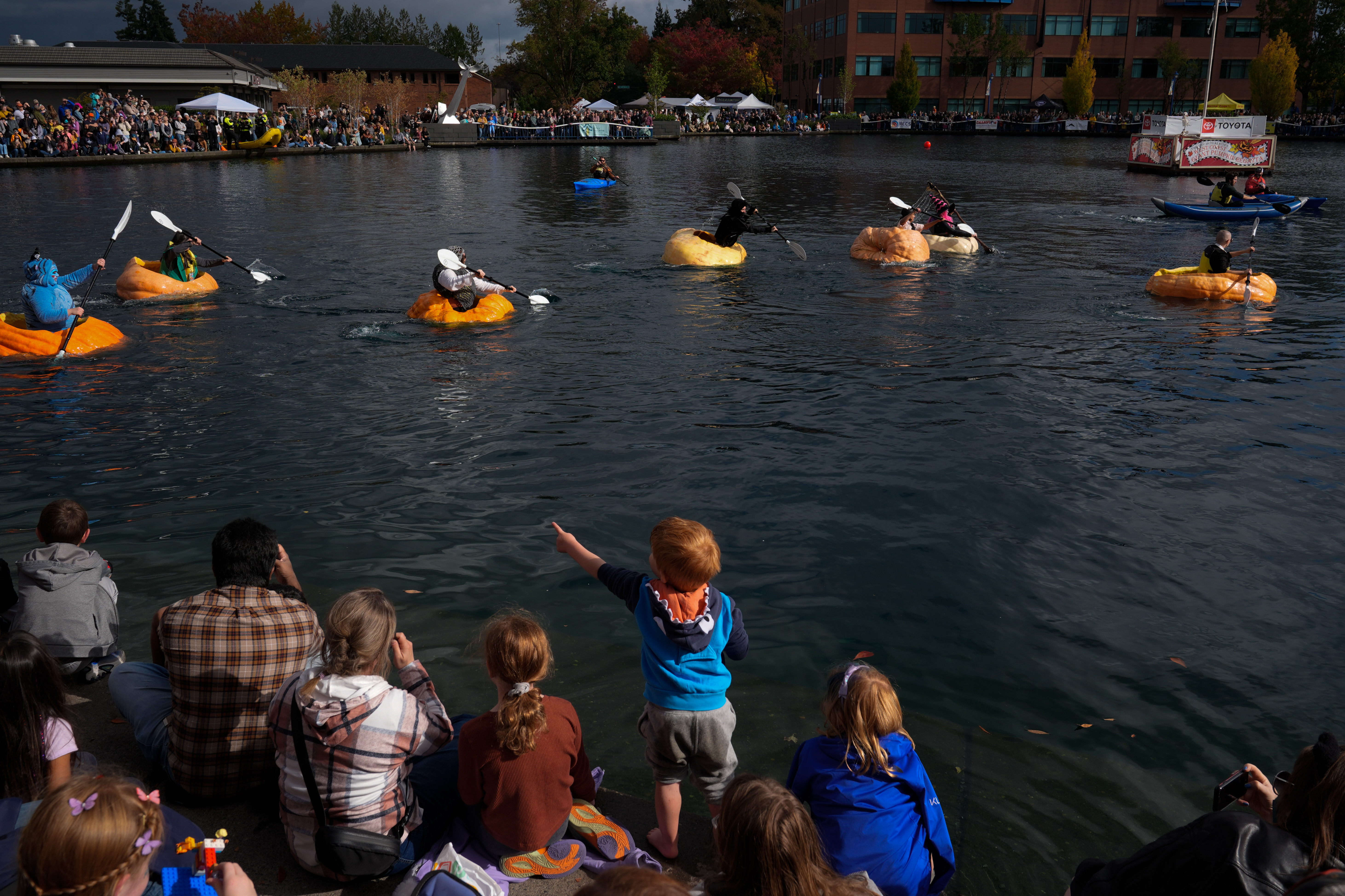 A child points to people racing giant pumpkins during the West Coast Giant Pumpkin Regatta on Sunday, Oct. 19, 2025, in Tualatin, Ore.
