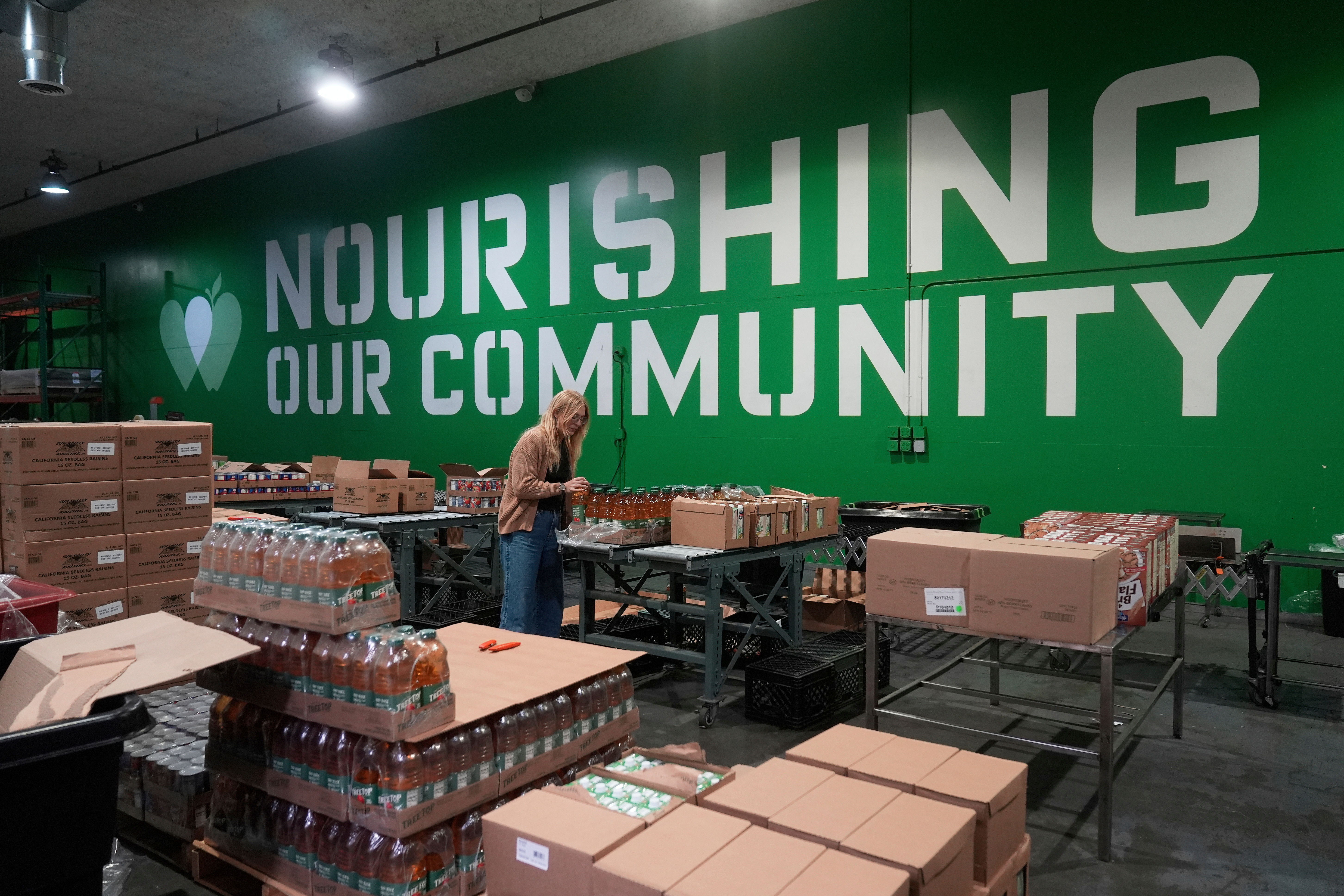 Mara Sleeter, marketing and communications project manager, stands near boxes of juice while being interviewed in the San Francisco-Marin Food Bank warehouse in San Francisco, July 2, 2025.