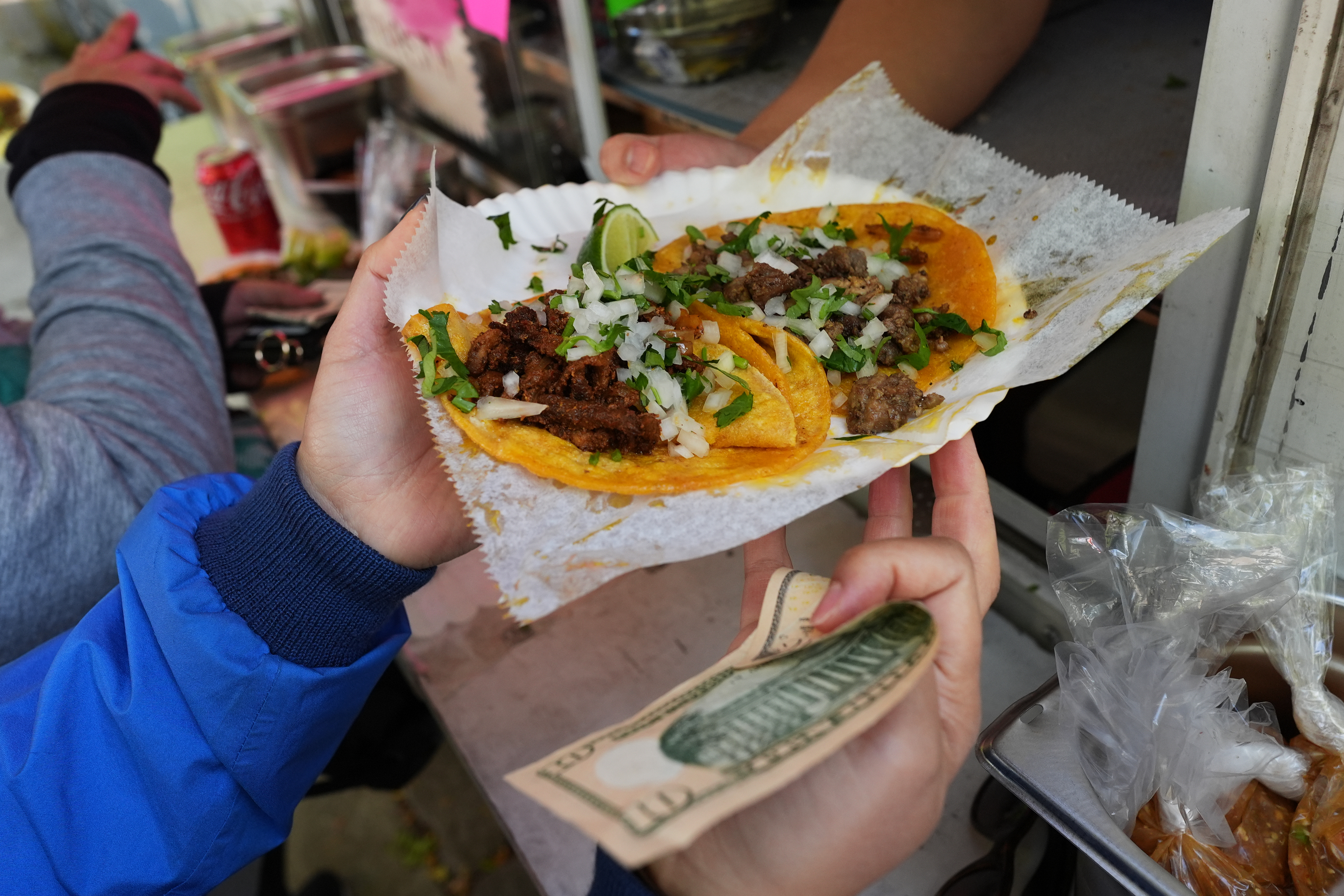 A bicyclist receives food from a street vendor Yulisa Robles, right, at Gage Park during Street Vendor Bike Tour Series, Chicago, Nov. 2, 2025.