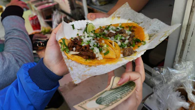 A bicyclist receives food from a street vendor Yulisa Robles, right, at Gage Park during Street Vendor Bike Tour Series, Chicago, Nov. 2, 2025.