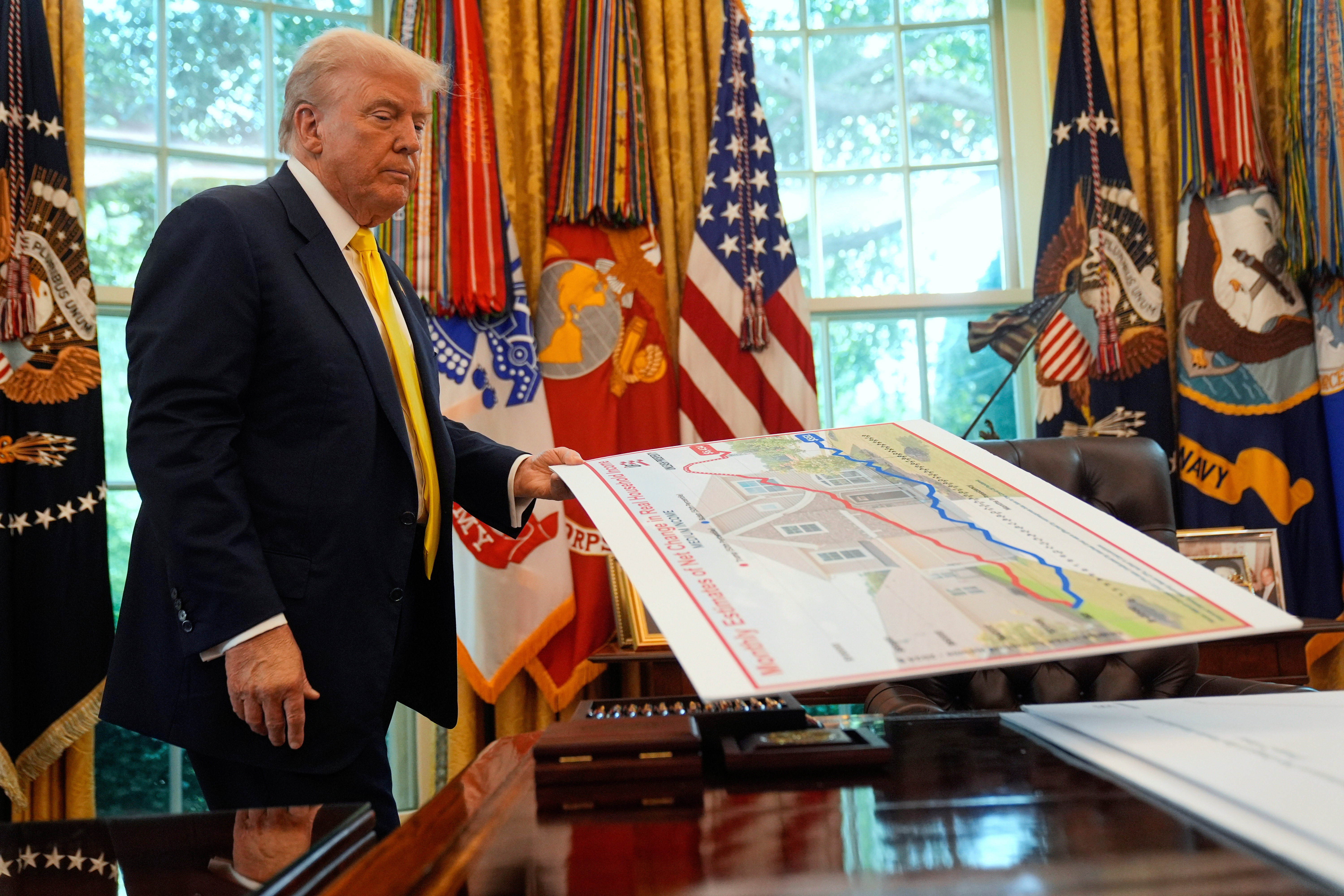 President Donald Trump holds a chart as he discusses the economy in the Oval Office of the White House, Aug. 7, 2025.