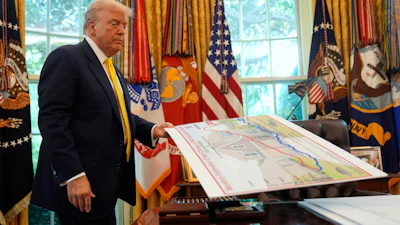 President Donald Trump holds a chart as he discusses the economy in the Oval Office of the White House, Aug. 7, 2025.