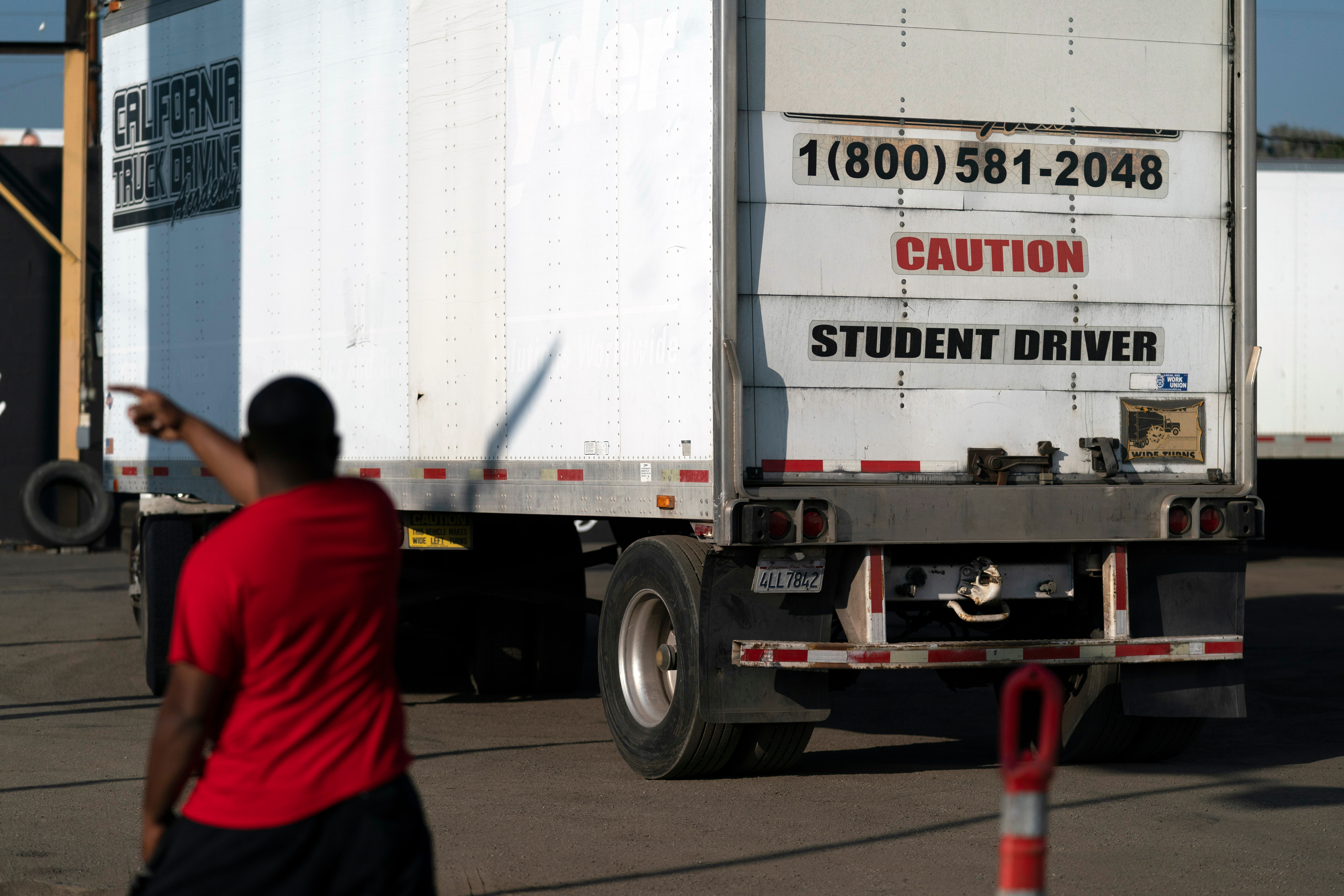 A student driver helps his classmate steer the wheel into the right direction as they practice driving in reverse, Nov. 17, 2021.