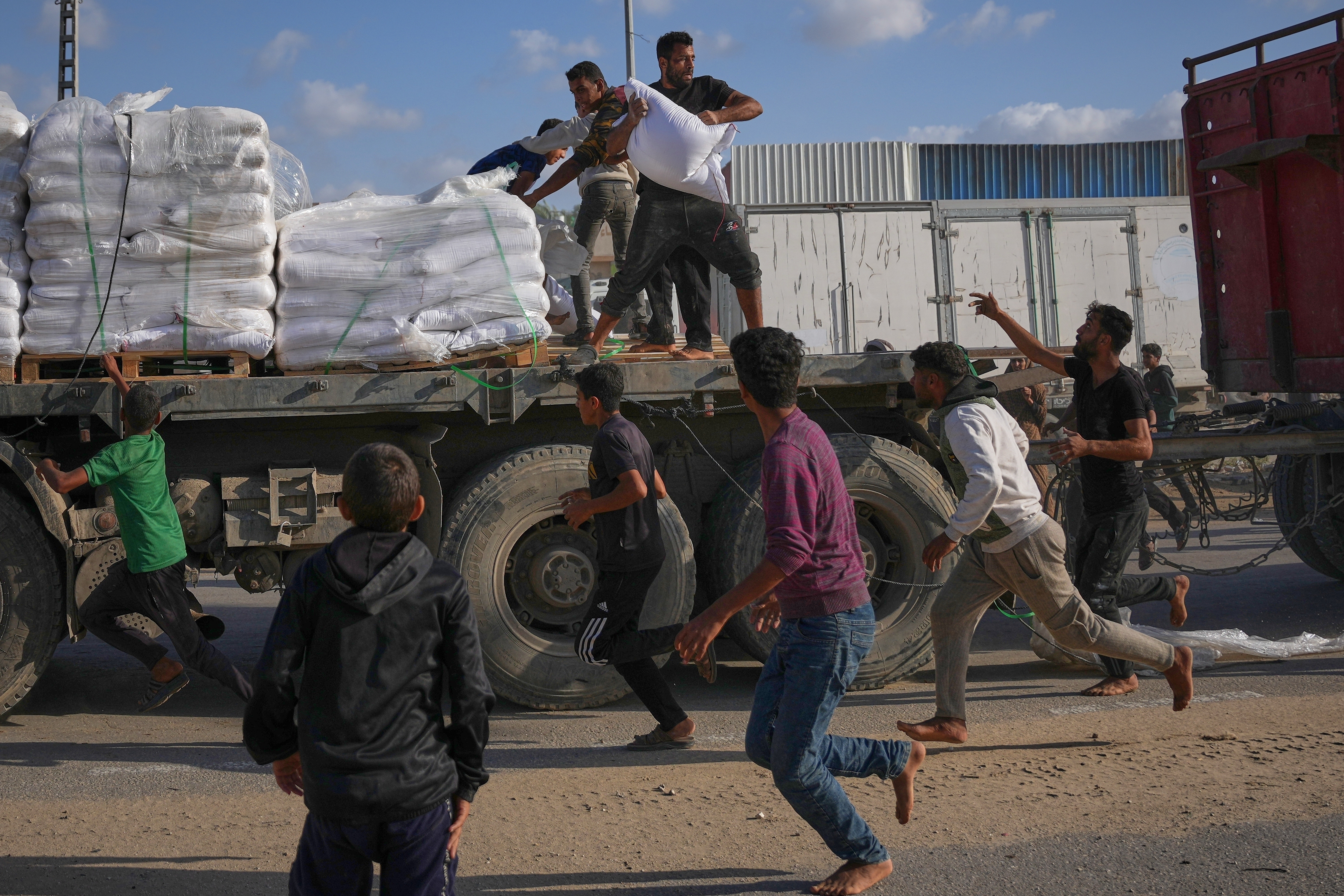 Palestinians grab sacks of flour from a moving truck carrying World Food Programme aid as it drives through Deir al-Balah in central Gaza, Nov. 15, 2025.